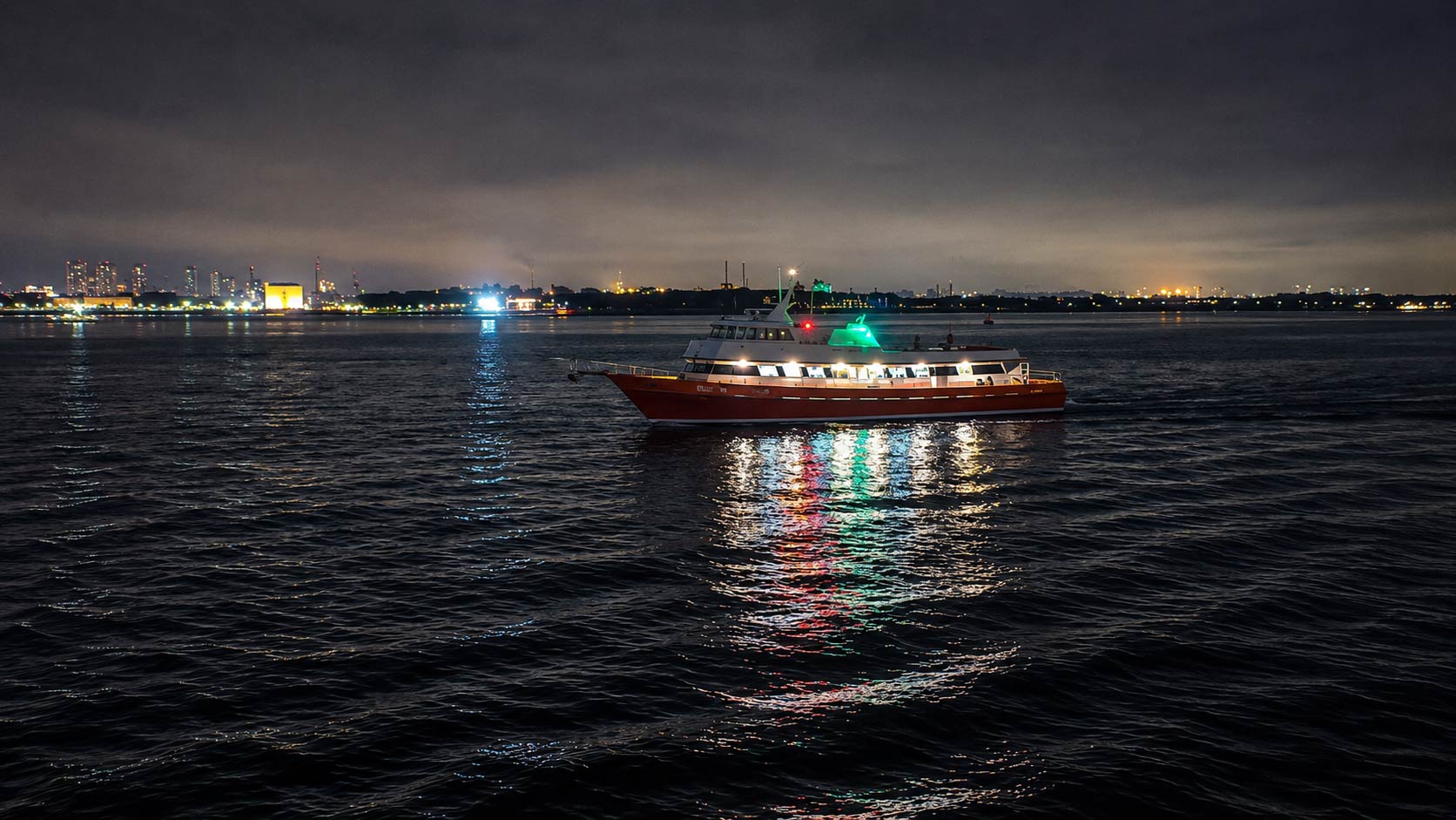 Lower Manhattan skyline illuminated at night from New York Harbor